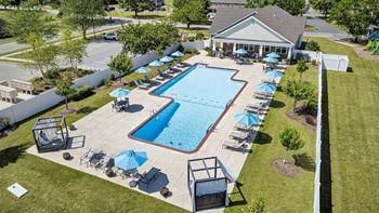 Outdoor pool and gated pool area with lounge seating, benches and tables